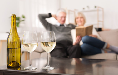 Senior Couple Looking Album, Drinking Wine At Home