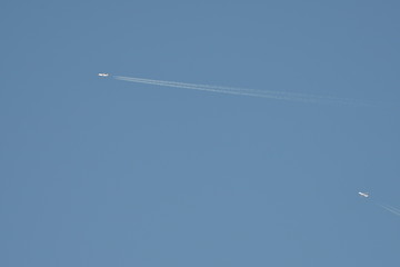 two airplanes with contrail in blue sky at very high altitude