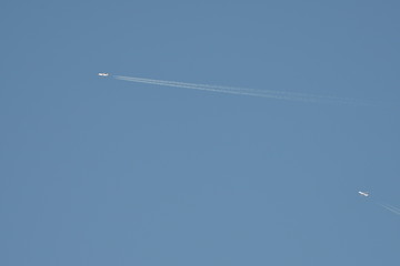 two airplanes with contrail in blue sky at very high altitude