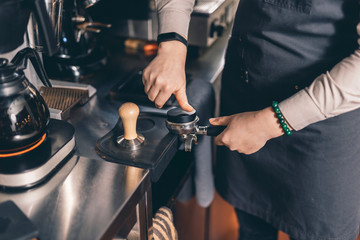 Barista making coffee pod in filter holder with round tamper
