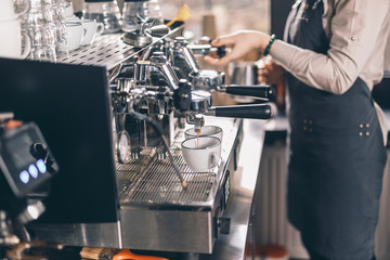 Coffee pouring into the cups while barista standing near