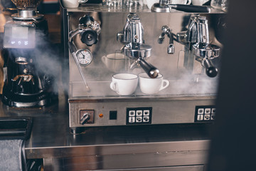 Cups on the drip tray with steam going from the steamer