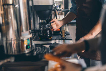 Hand of barista taking coffee jug by the handle