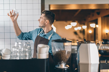 Enthusiastic barista checking the glass by putting it up