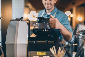 Selective focus of the coffee jug warming up at the bar counter