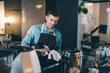 Smiling young man drying clean tamper with soft towel
