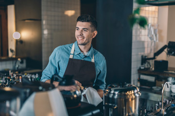 Fototapeta premium Confident barista looking away while cleaning tamper