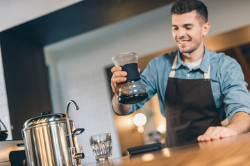 Optimistic young barista putting drip decanter up
