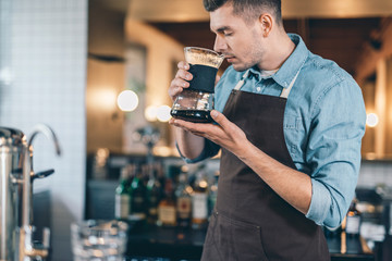 Concentrated barista smelling coffee with closed eyes