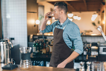 Barista at the bar counter drinking coffee alone