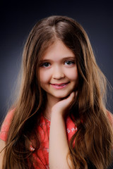 Fototapeta premium Studio portrait of a girl 6-7 years old .Cute little girl posing in studio on dark background.
