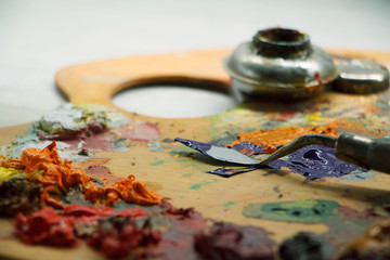 Closeup of palette with colorful paints and spatula on white surface, background - Powered by Adobe