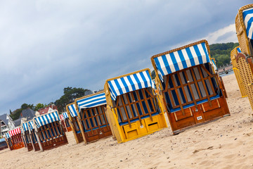 Colorful striped wooden hooded beach chairs (strandkorb) on a sandy Baltic beach in Luebeck-Travemunde seaside resort, Schleswig-Holstein, Germany