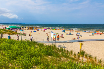 Fototapeta na wymiar Сrowded Baltic beach on Usedom island in Swinoujscie resort, Poland. It borders the German seaside resort of Ahlbeck, both are freely connected by 12km of beach promenade