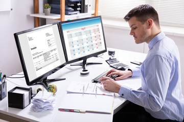 Fototapeta na wymiar Businessman Calculating Invoice In Office