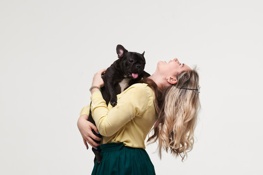 Veterinary concept. Happy hipster woman playing with french bulldog on white background. Owner with funny dog resting, hugging and having fun. space for text