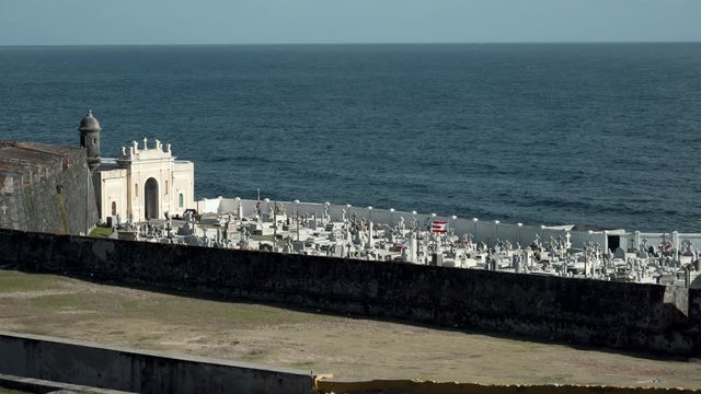 The Puerto Rican flag proudly waves in a cemetery in Viejo San Juan, Puerto Rico, by the ocean on a moody day.