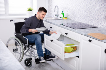 Disabled Man Sitting On Wheelchair Arranging Plates