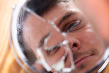 Reflection Of A Man's Face In Broken Mirror