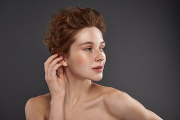 Fototapeta premium Beautiful red-haired girl with natural makeup touching her ear