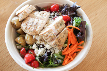 farm fresh bowl of salad greens with tomatoes carrots and grilled chicken