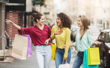 Young women walking with shopping bags on street
