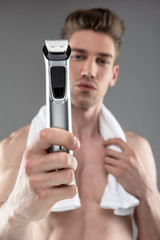 Attractive young man with towel holding electric razor