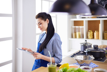 Young woman using a tablet computer to cook in her kitchen