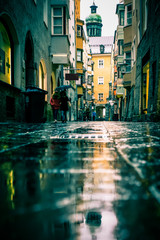 Street scene on rainy day in Innsbruck Austria with old architecture, puddles, reflections, umbrellas and unrecognizable people
