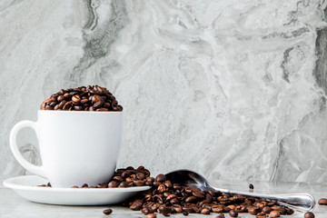 Black coffee in cup and coffee beans on marble background. Top view, space for text