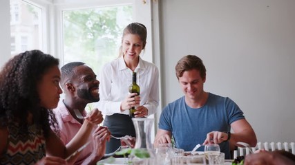 Waitress Serving Wine To Group Of Friends Eating Meal In Restaurant Together 