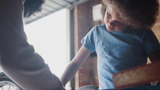 Close up of pre teen boy standing at a workbench concentrating on screwing in a bolt while building a racing kart with his father, selective focus