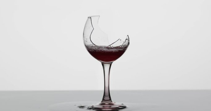 Wine. Red wine pouring in broken wine glass on the wet surface