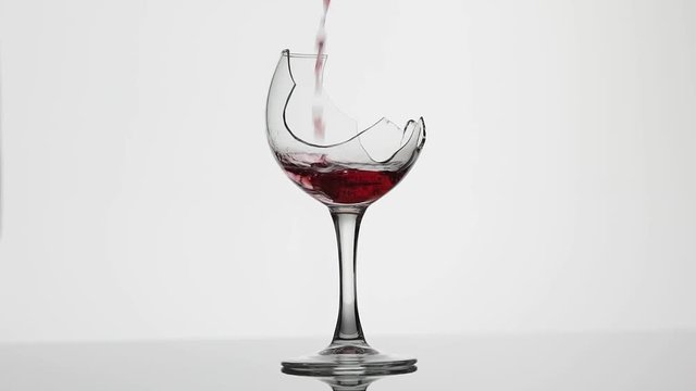 Wine. Red wine pouring in broken wine glass on the white background