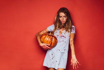 Halloween girl vampire with bloody pumpkin. Portrait of a woman with make up blood on her face. A beautiful, sexy woman, a vampire, all in blood, with a flow of blood near the lips. © Volodymyr