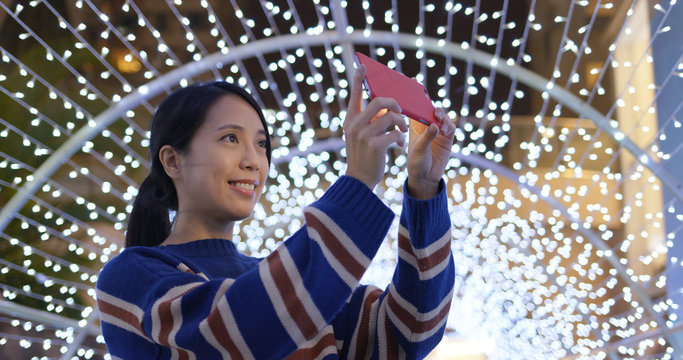 Woman take photo on cellphone with the beautiful lighting decoration in city at night