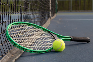 Close up of tennis ball and racket on court from the prospective of the net