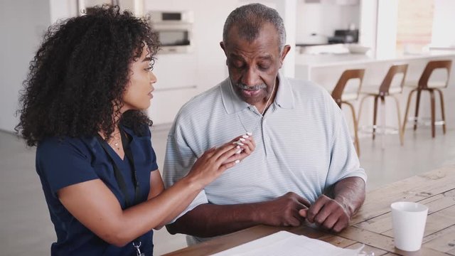 Female healthcare worker showing a senior man how to use an assistance alarm during a home visit