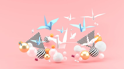 A paper bird among colorful balls on a pink background.-3d rendering.