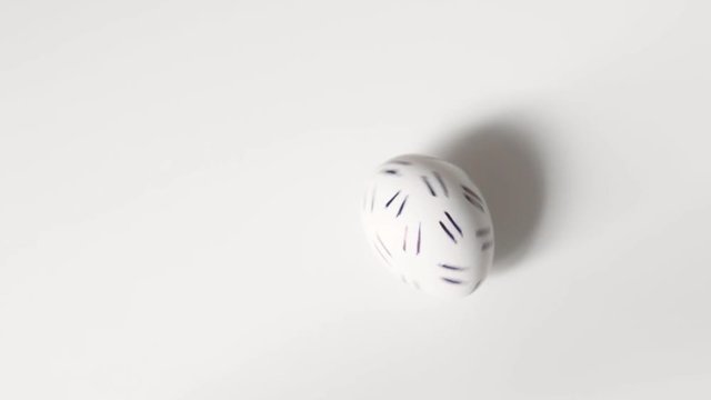 Egg spinning.Chicken egg spinning on white background top view. Egg spinning and rolling on the white background Happy Easter.Easter painted egg spinning on a white background.