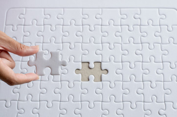 Hands putting piece to white jigsaw puzzle,Concept partnership business successful teamwork