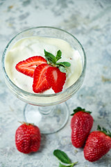 Ice cream with strawberries in a glass vase. Gray textured background. Dessert