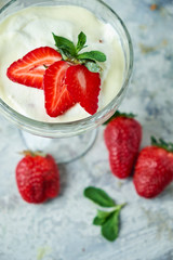 Ice cream with strawberries in a glass vase. Gray textured background. Dessert