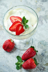 Ice cream with strawberries in a glass vase. Gray textured background. Dessert