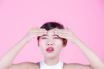 Fototapeta premium Facial skin problems women - unhappy young women touching her skin on a pink background.