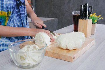 A beautiful woman is cutting vegetables in the kitchen at home.