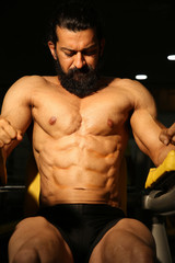 Fototapeta na wymiar Asian Indian beard strong man bodybuilder athletic fitness man pumping up abs muscles workout in gym bodybuilding concept - Image