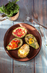 Avocado baked with egg and a variety of stuffing. Presented on a table of blue boards
