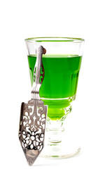 Alcoholic drink, creative stimulant and bohemian lifestyle concept theme with glass of green absinthe and stainless steel spoon isolated on white background