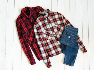 Clothes concept. Two checkered shirts and jeans on a wooden background. Top view
